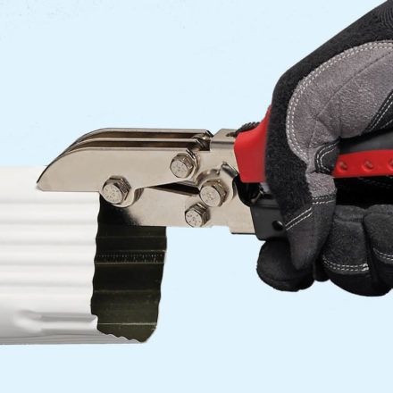 Gloved hand crimping a white gutter downspout with Malco's 5-blade C4R tool
