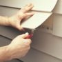 Worker using Malco's Vinyl Siding Removal Tool to remove vinyl siding on a house